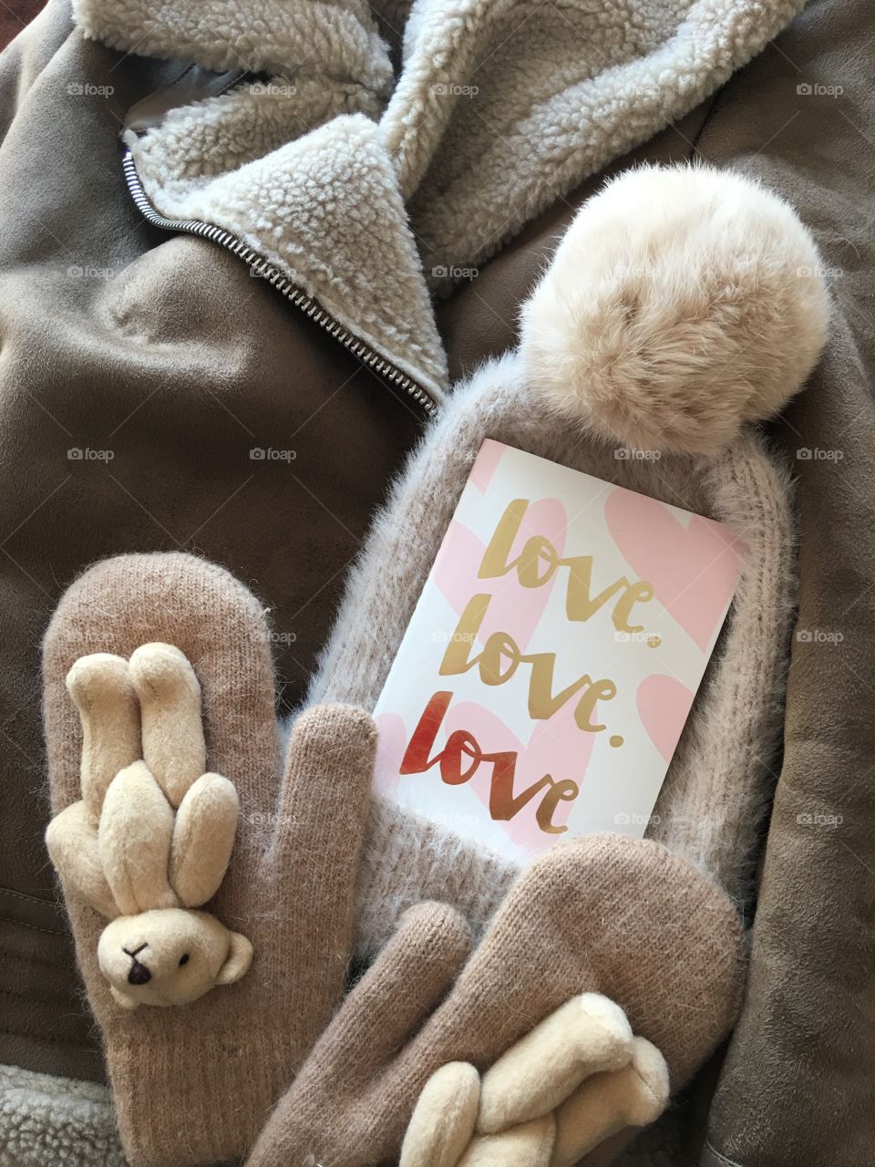 Flat lay items. Winter hat, card with inscription love, mittens lying on coat