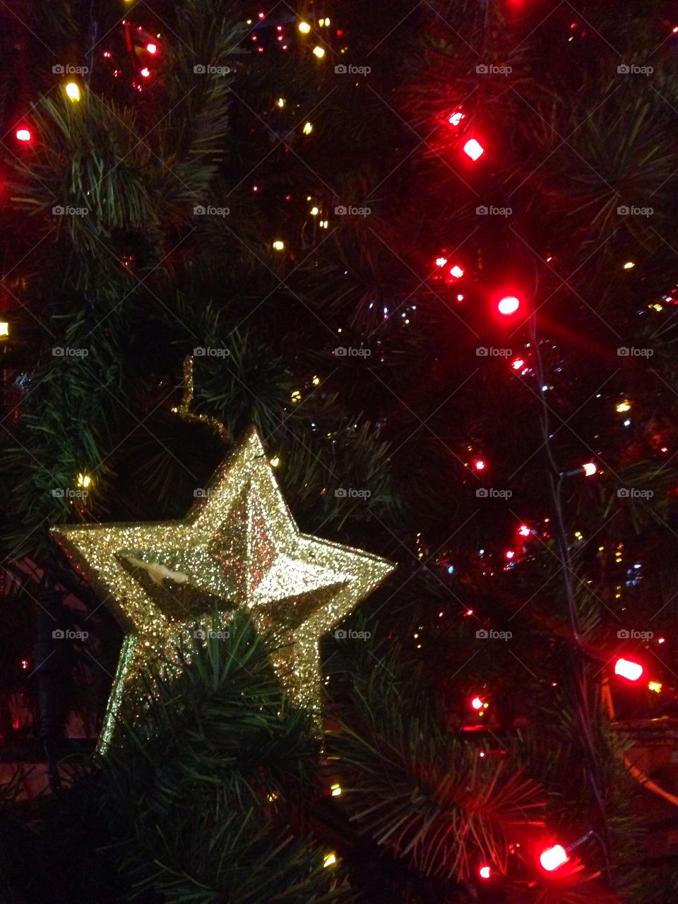 Gold plastic star, balls, red lights garland and other Christmas decorations on artificial fir tree in Moscow, Russia