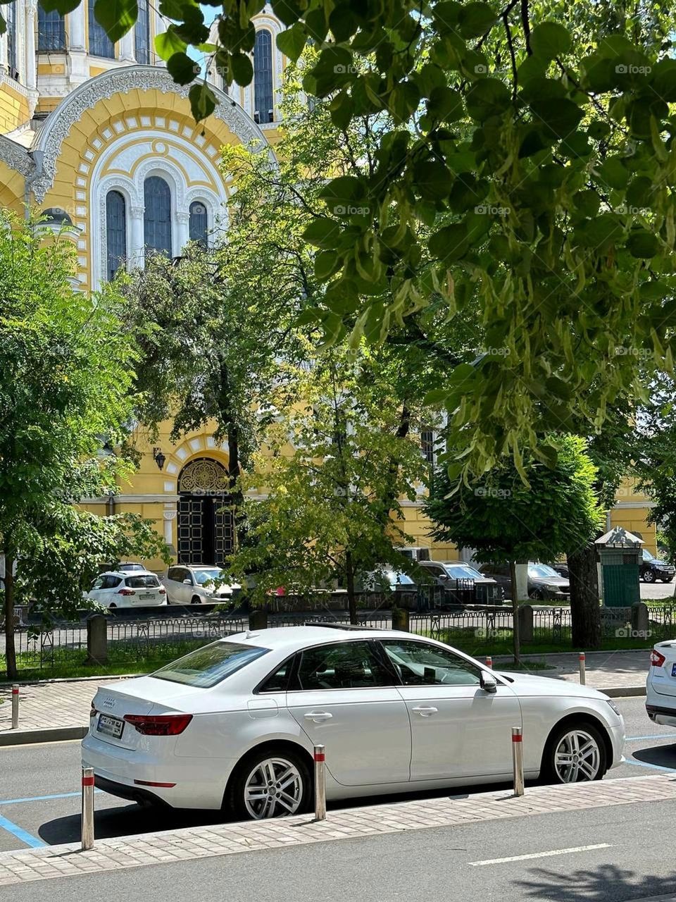 Elegant white car against the backdrop of urban greenery