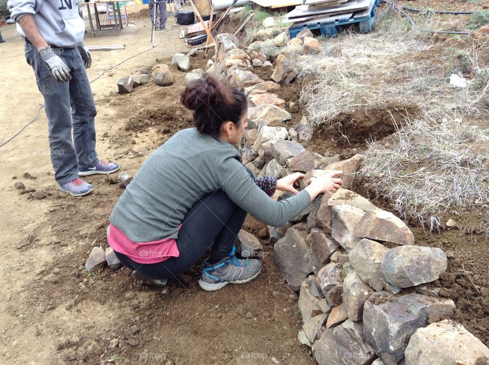 Woman building a dry stone wall.