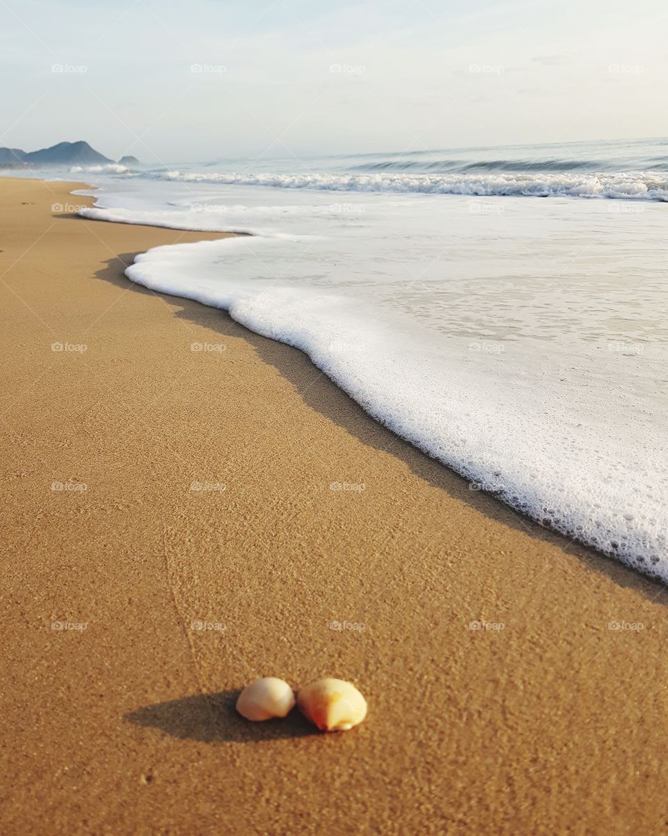 Sea foam on sandy beach