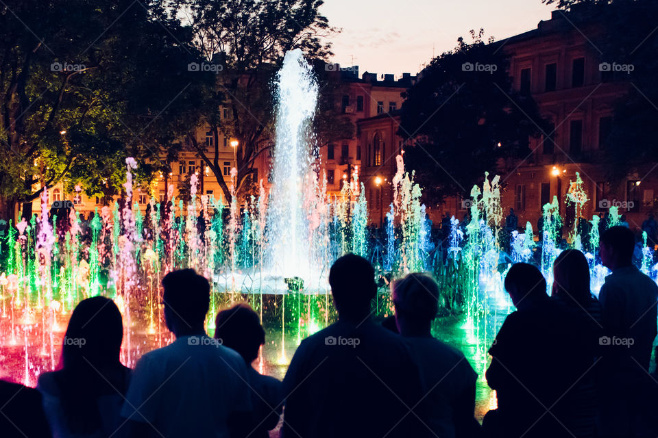 People looking at fountain and lights in the evening in the center of Lublin
