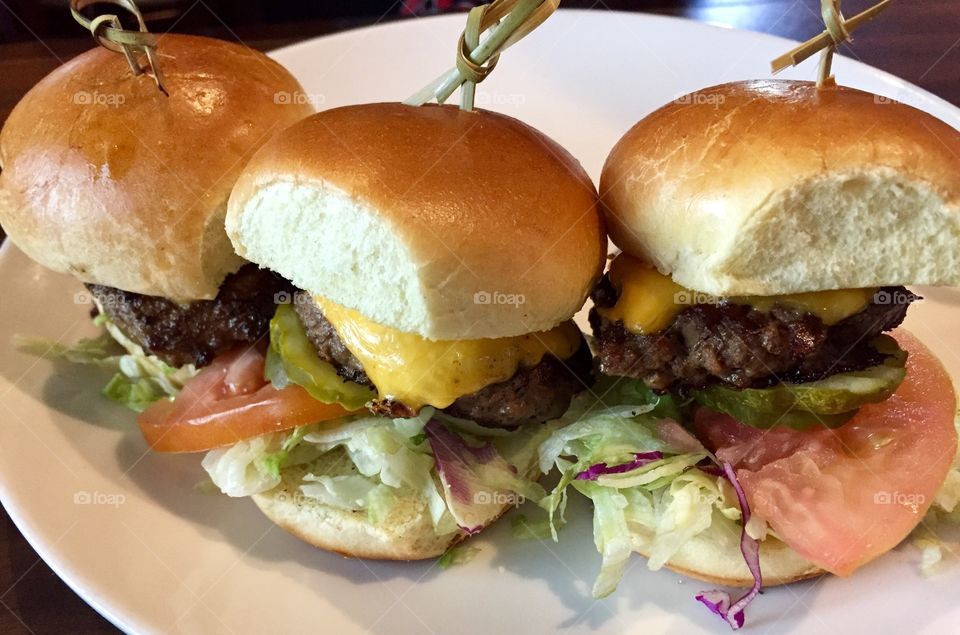 Three cheeseburger sliders on a platter