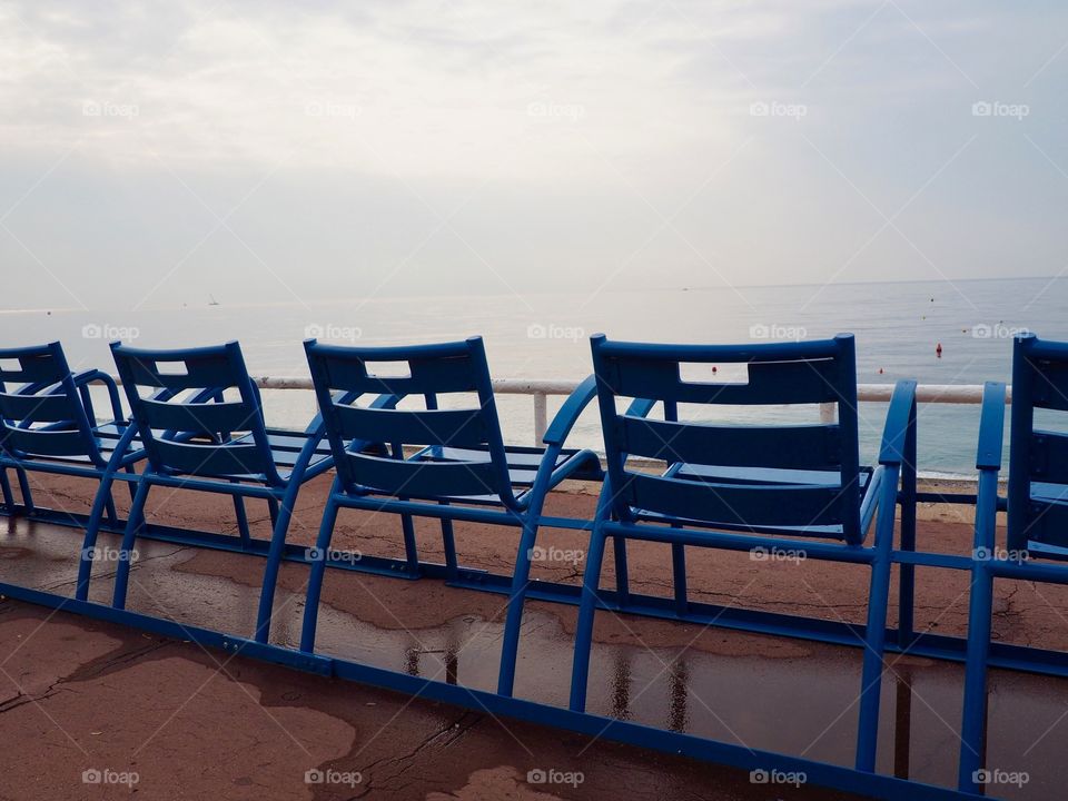 Iconic blue chairs on the Promenade des Anglais overlooking the sea.