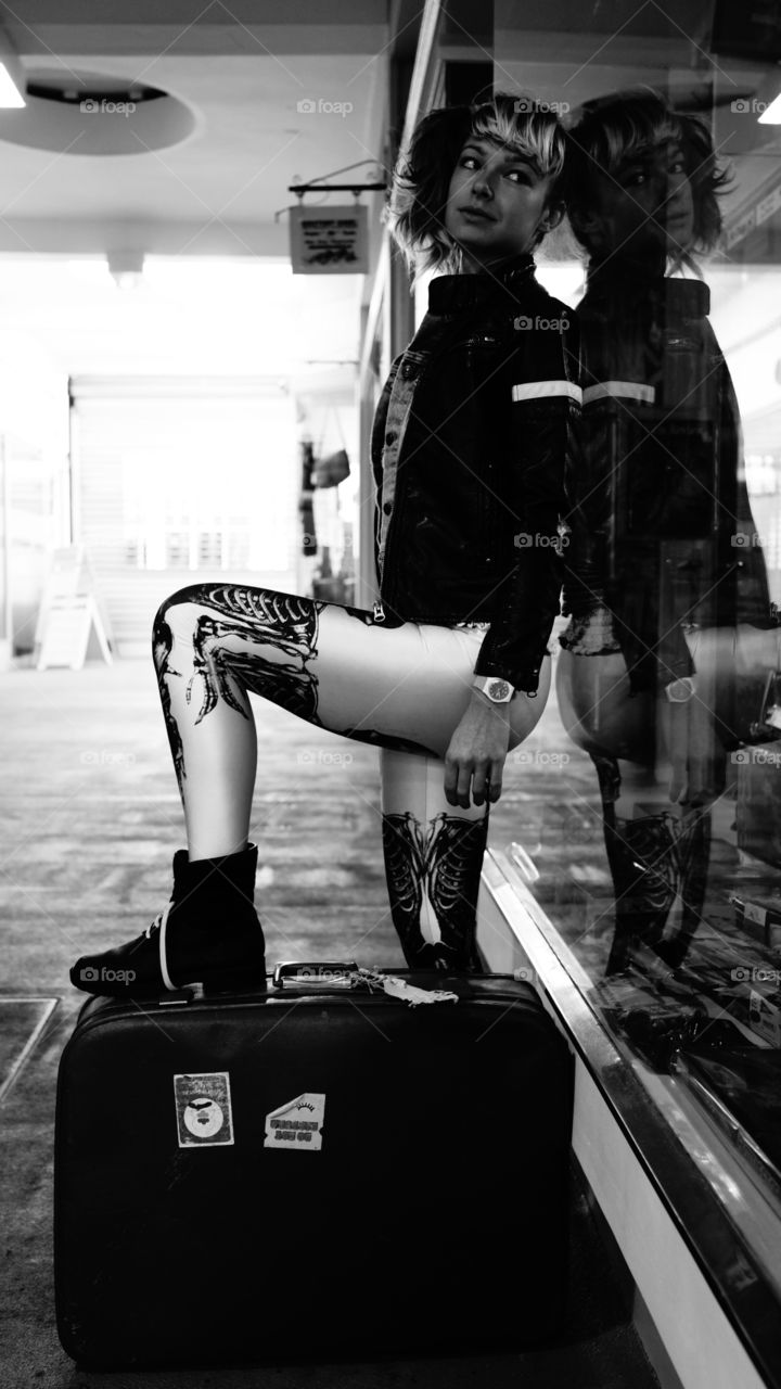 Young girl posing with suitcase near glass wall