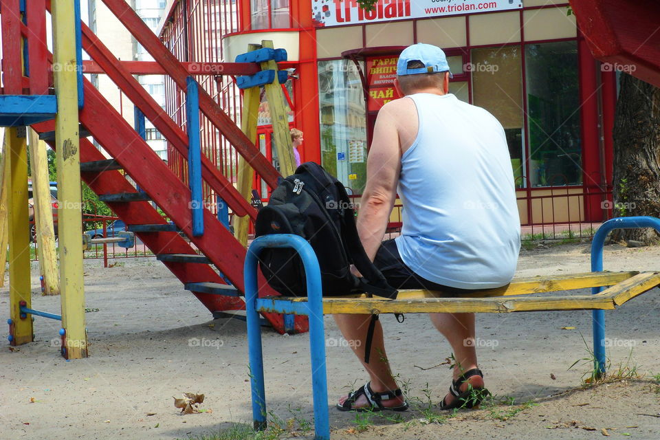 a man is sitting on a bench near a playground