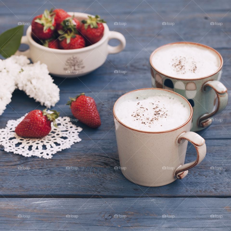 2 cups of coffee and strawberry on a blue wooden table