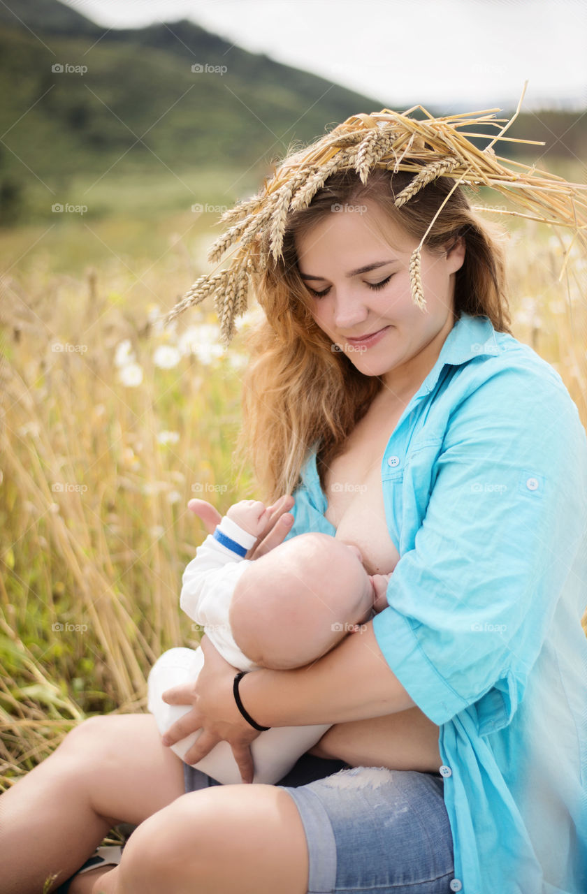 Mother breastfeeding her baby at wheat field