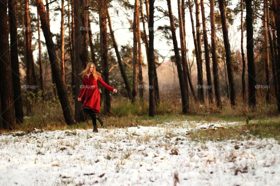A girl walks through the winter forest in the evening
