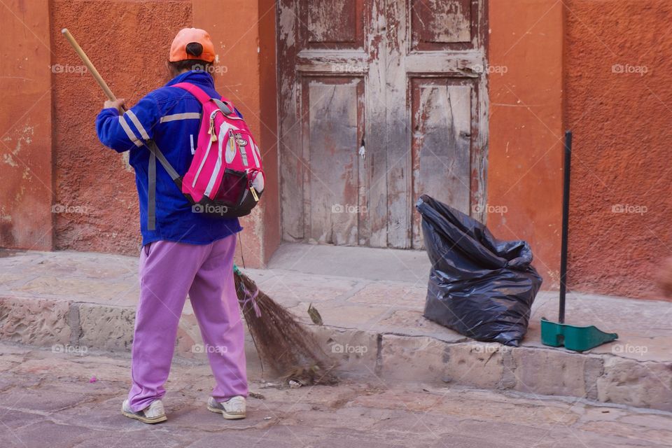 Rear view of woman cleaning road