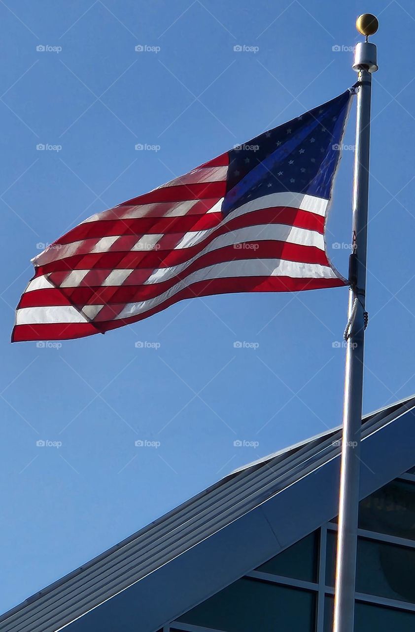 American flag blowing in the wind on a building flapole folded into a new pattern