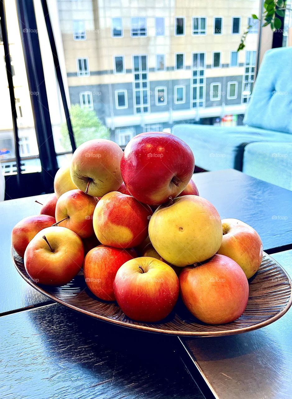 The photo shows a plate of apples. The apples look fresh and appetizing, with glossy skin that reflects light. Their rich colors range from bright red to green, creating a beautiful contrast.