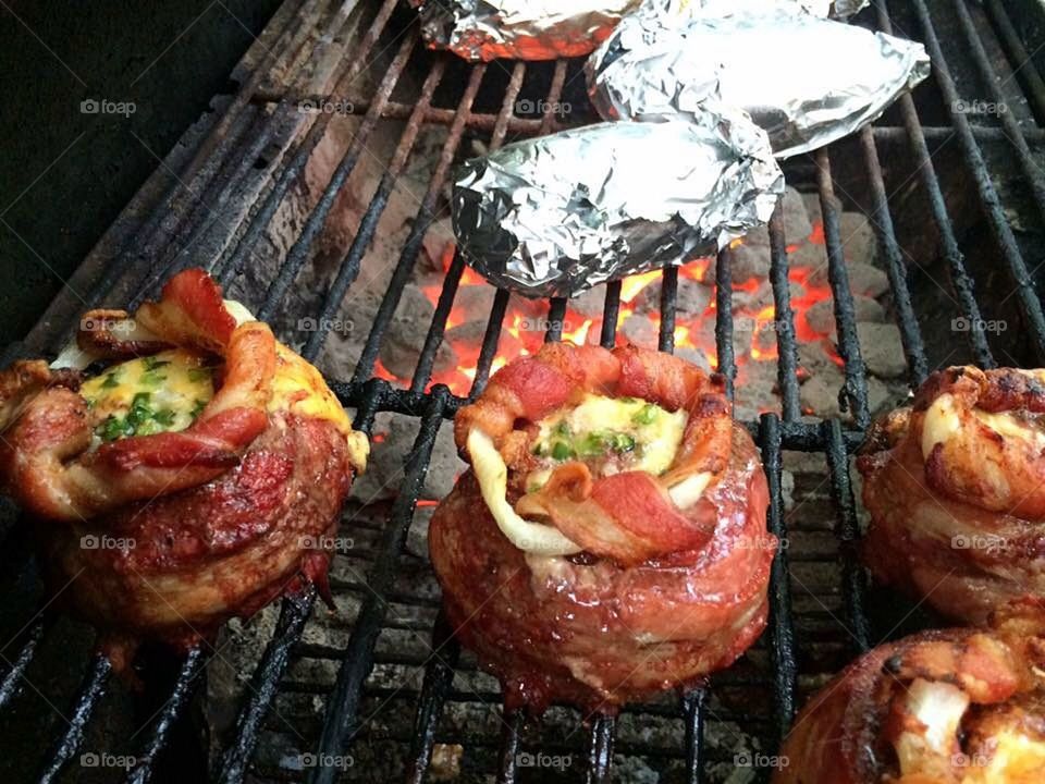 Grilling hamburgers wrapped in bacon with bacon wrapped onion rings