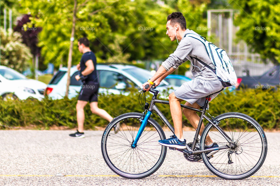 Young Man Riding Bike In City And Listening Music With Earphones