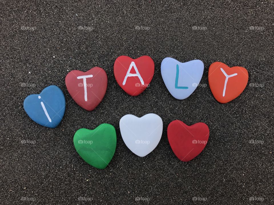 Italy, country name with colored heart stones over black volcanic sand