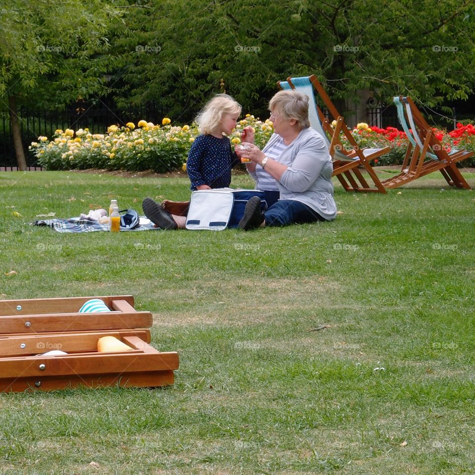 A lady and a little girl enjoying a picnic on a nice summer day at Regents Park in London. 