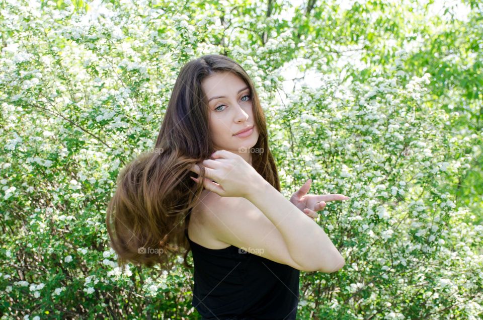 Beautiful Young Girl on Background of Flowers