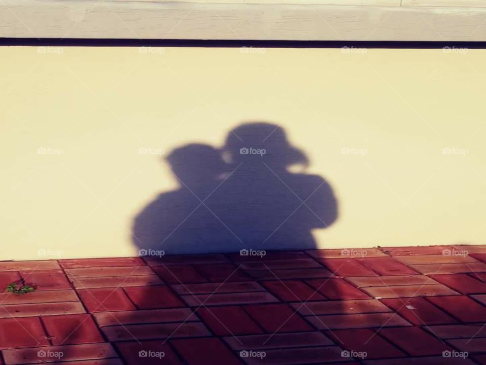 a shadow of a  child is who's walking around while the mother  is at her back following her  to assist her .