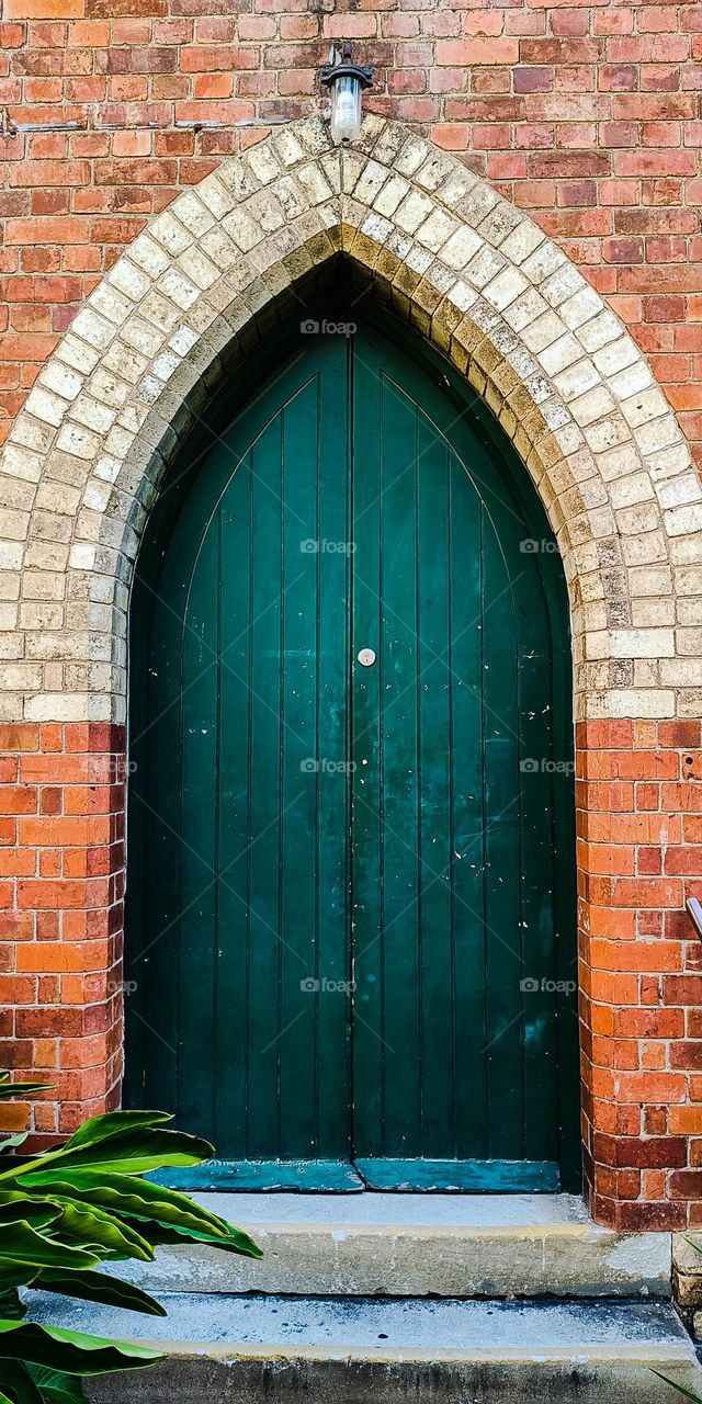 Old green wooden door on church brick wall