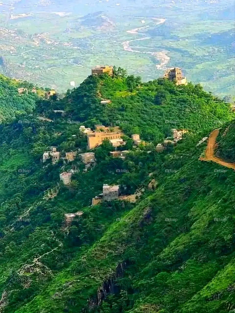 The image embodies a natural natural plate of the mountains of nature, where green agricultural stands are graded on the slopes as if they were lines of a poem, which fog harmoniously wrapped, and clouds hugged them in the mountain knife and the whis