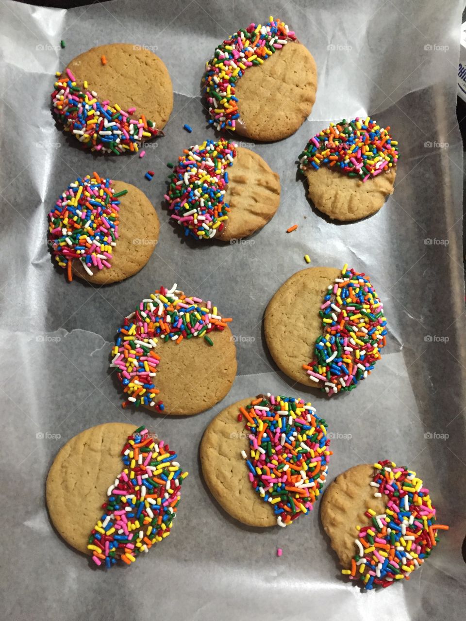 Peanut butter cookies dipped in melted chocolate and sprinkles