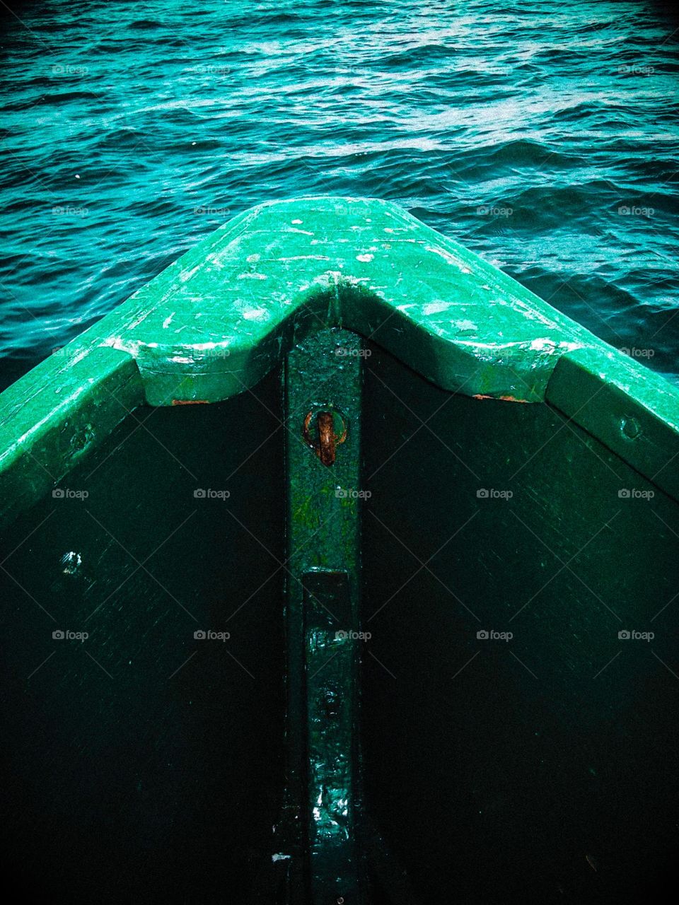 Bow of a green boat cutting through the pacific waters off the coast of Santa Cruz California, calm clear sailing ahead 