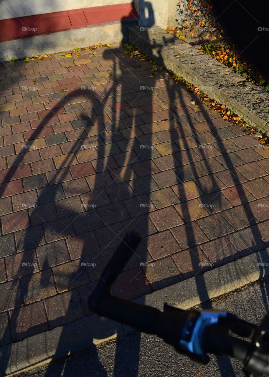 person with bike light and shadows on a street pavement on a sunset, abstract background