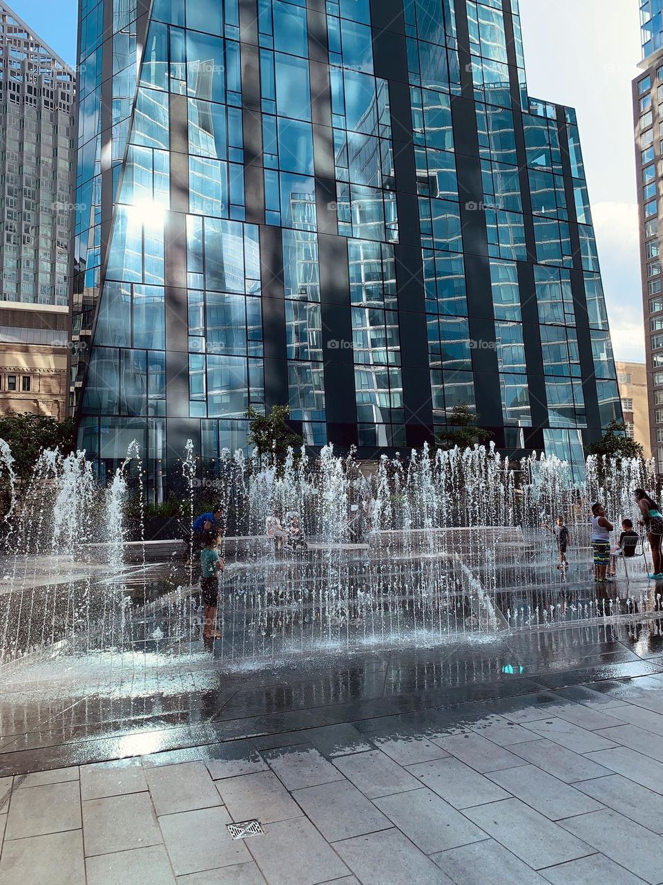 Kids are enjoying playing in a water fountain in front of waterline square condominium residence and office building, Manhattan New York.