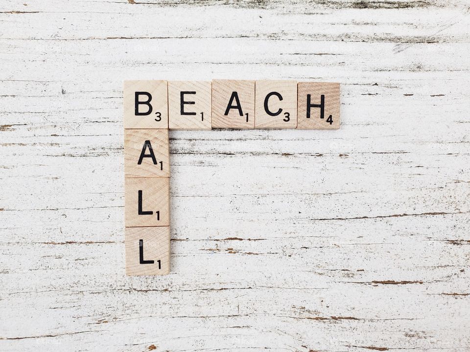 Beach ball wooden square word tiles on a rustic white background 