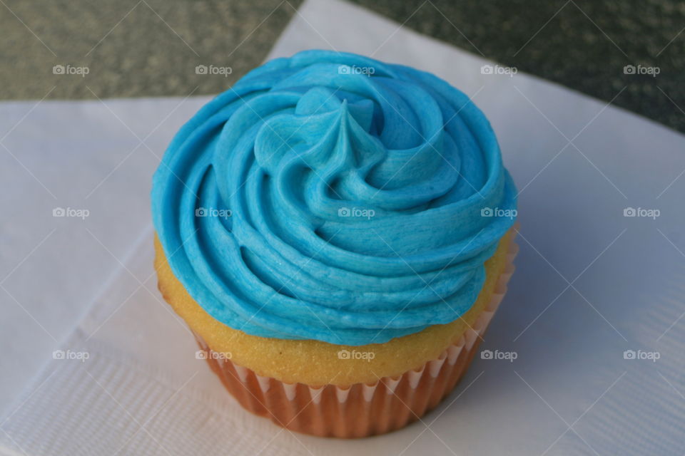 Yellow cupcake with buttercream icing tinted blue. 