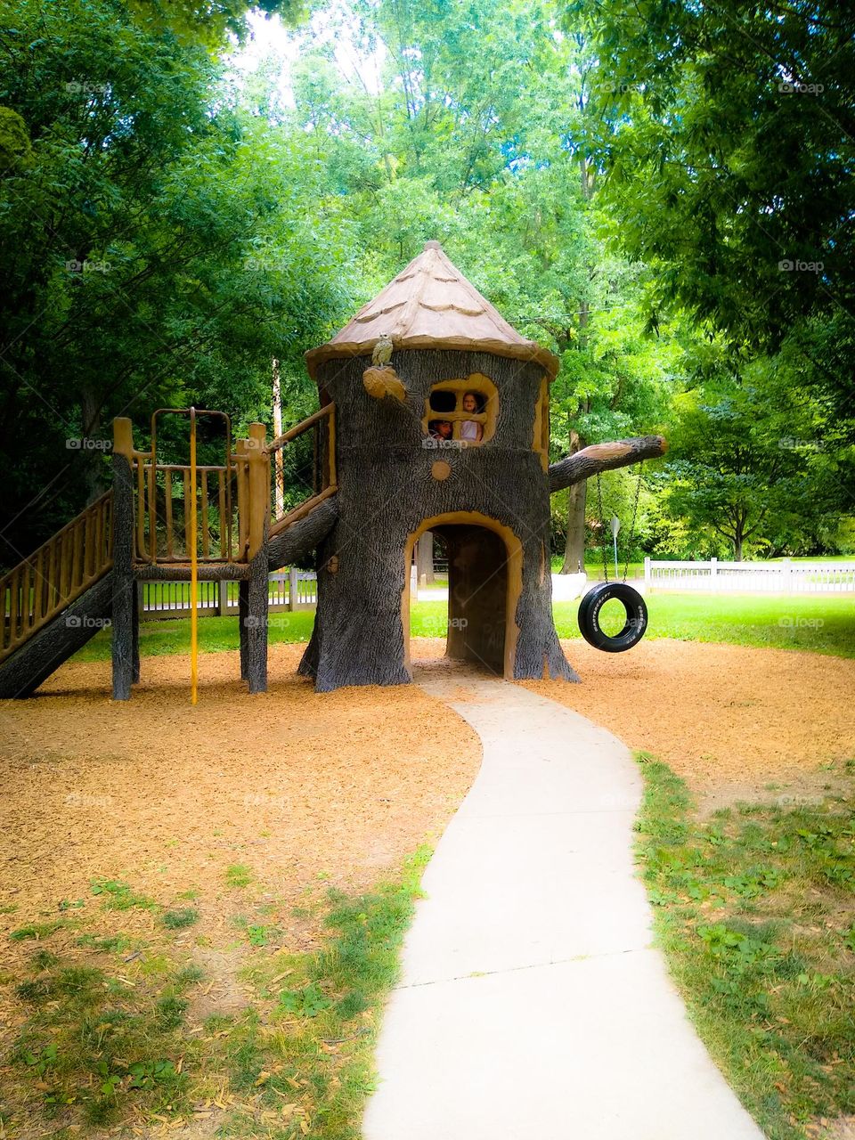 A quite literal tree house with tire swing and staircase in Wooster park Ohio surrounded by lush green trees and mulched 