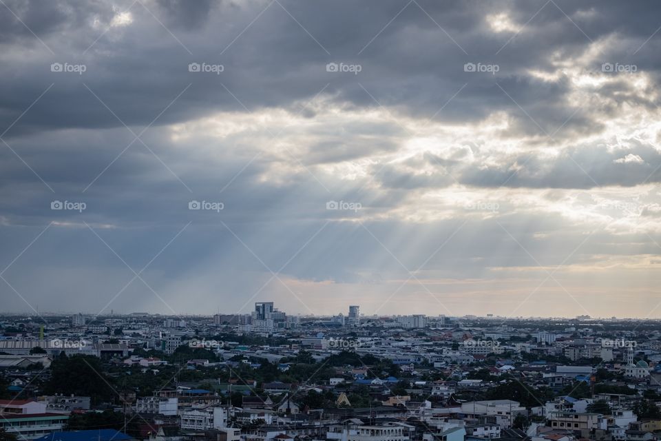 Beautiful sun light beam pass through Cloudy sky over city scape before rain in Bangkok Thailand 