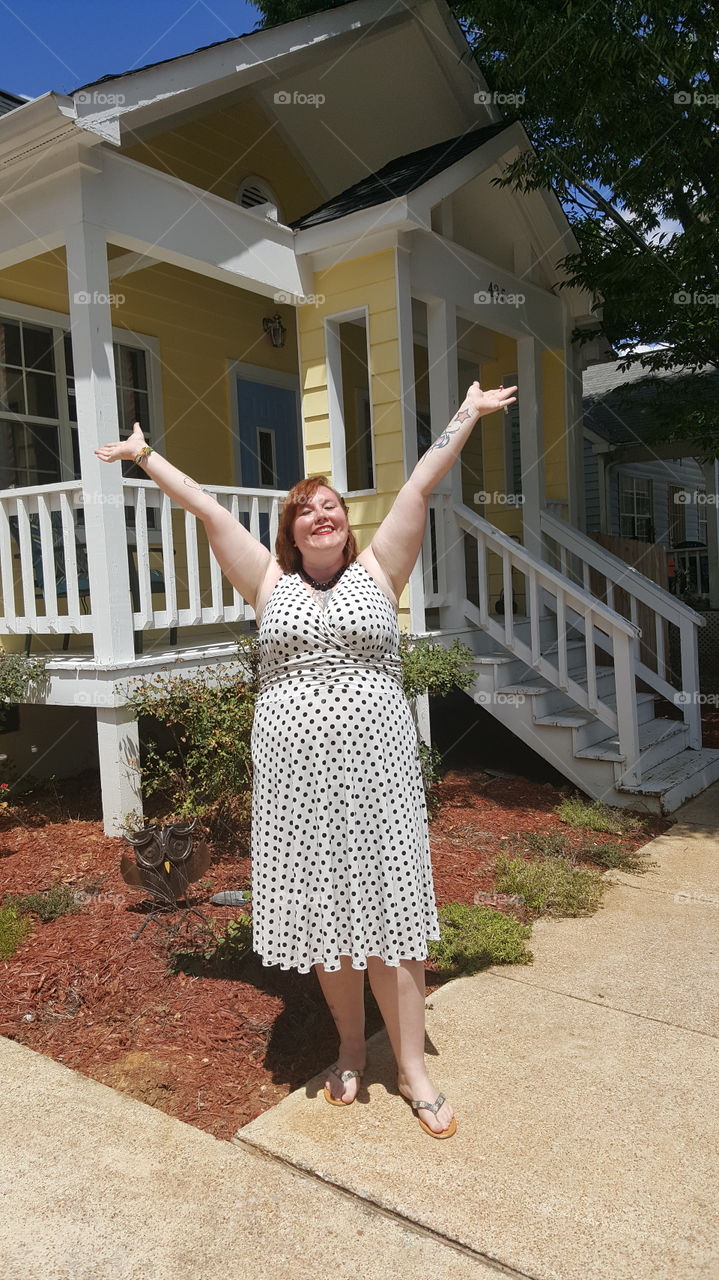 New home owner celebrating the joy of new adventures in the summer. Redhead in polka dot dress.