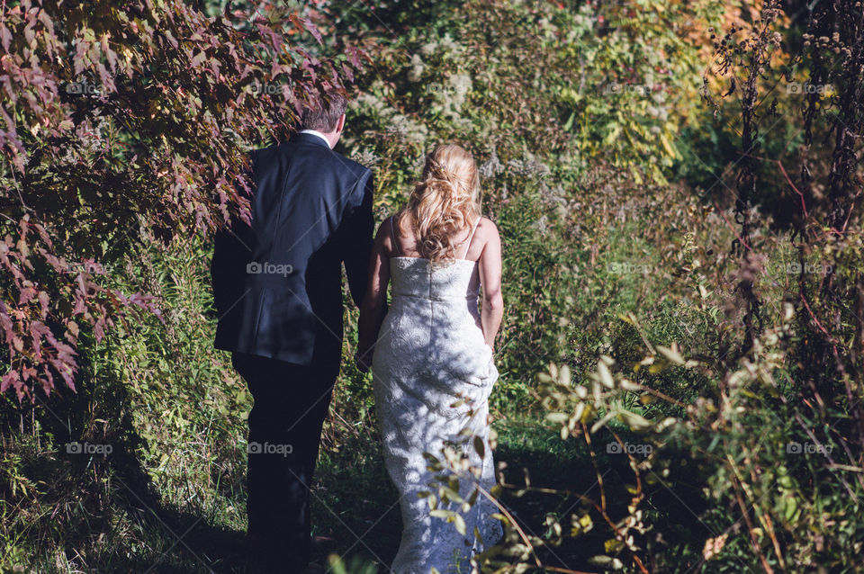 Bride and groom walking away from camera in outdoor garden