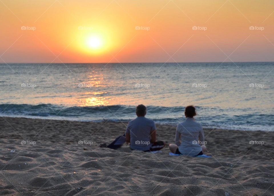 Couple Doing Yoga Outdoor at Sunrise on the Beach