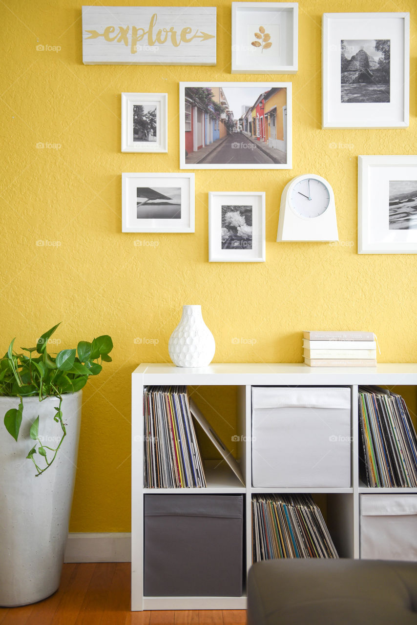 Modern boho chic interior design with square and rectangular shelves and picture frames against a yellow wall