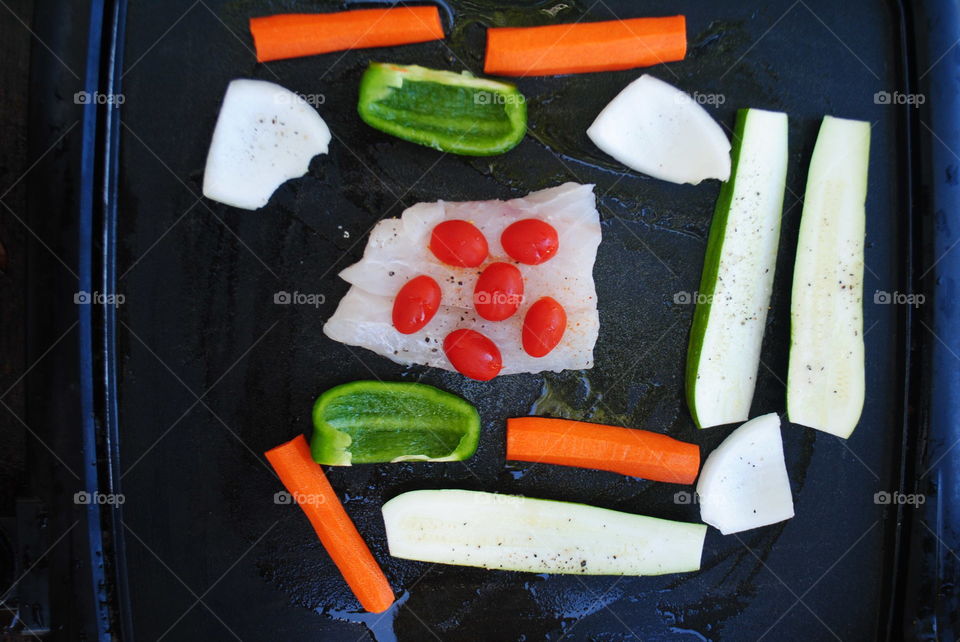 Cooking fish with vegetables at the grill outside