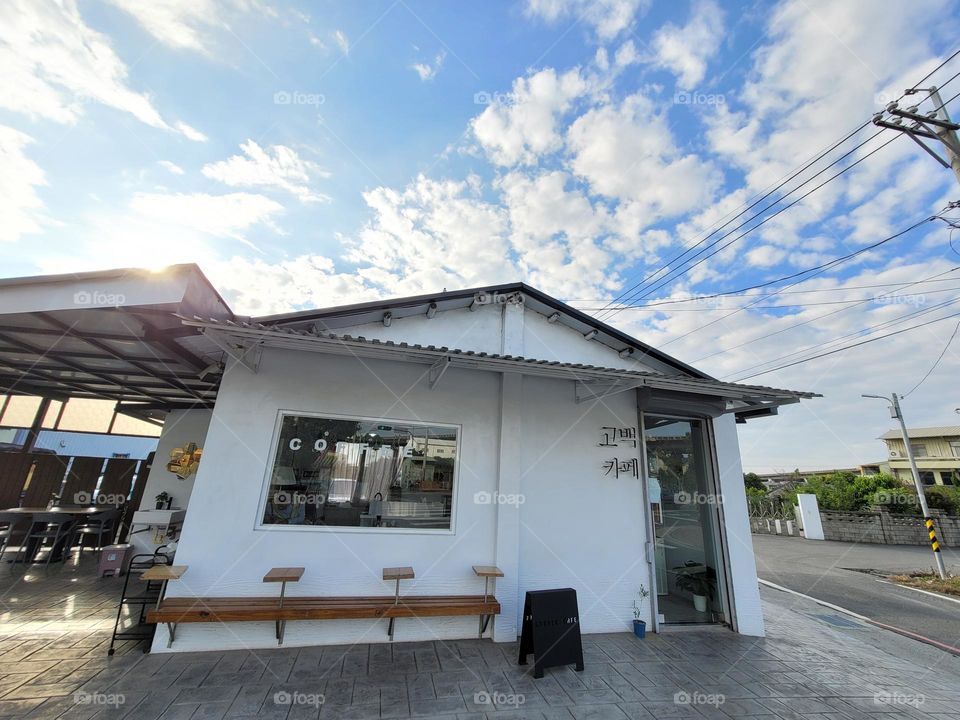 A day of good weather, blue sky and white clouds, white building, a cafe with outdoor seating