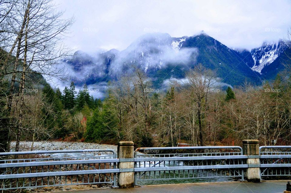 bridge over a river with beautiful snowcapped mountains