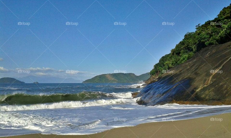 Ondas bonitas na paisagem à beira da rocha na praia no Brasil.