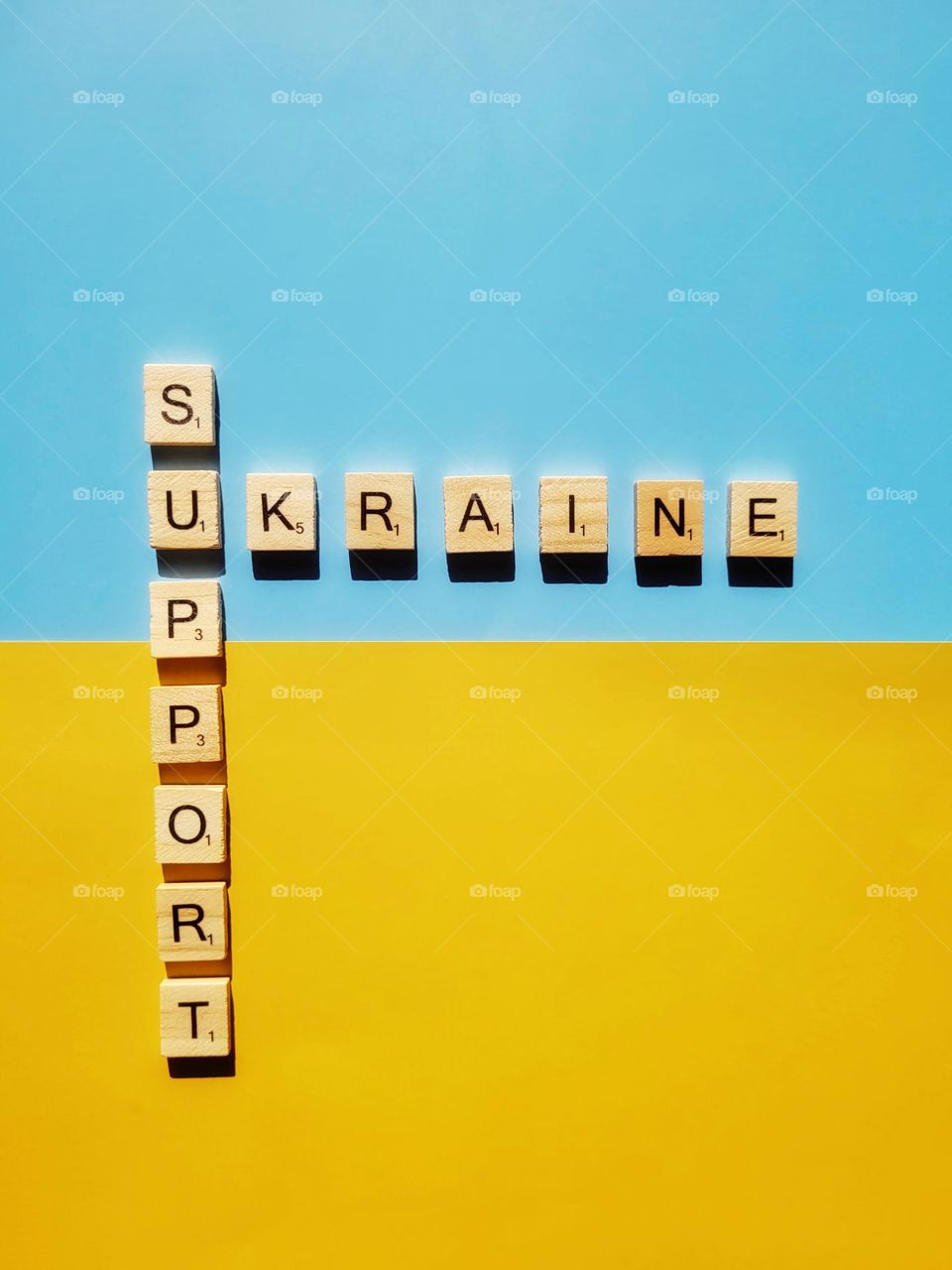 Top view of cube beads with words Support Ukraine close up.  Creative idea of freedom.  Blue, yellow background.