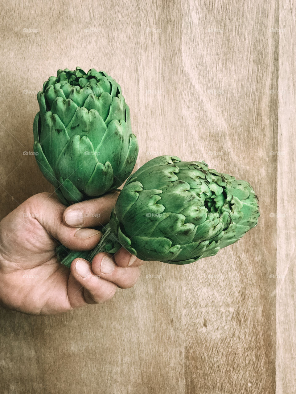 Hand holding green artichokes