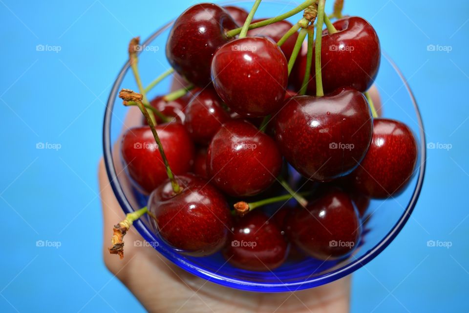 Person holding bowl of cherries