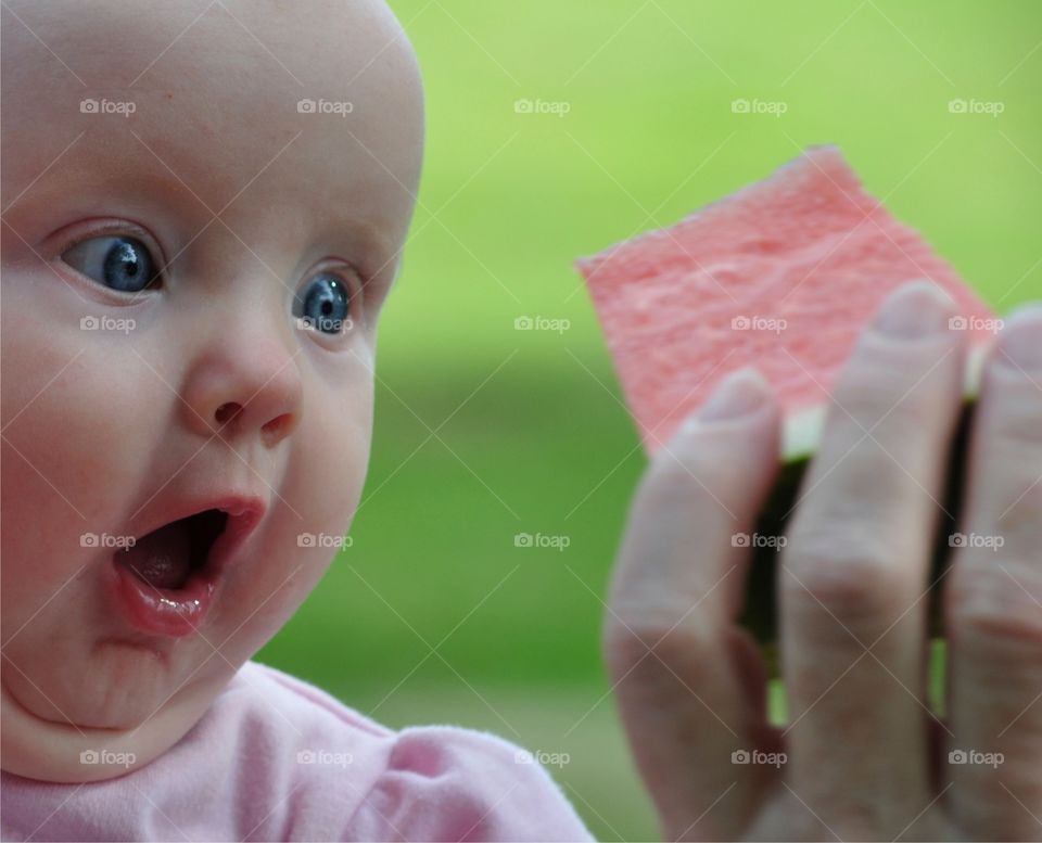 Watermelon Surprise . Infant looking anxiously at slice of watermelon 
