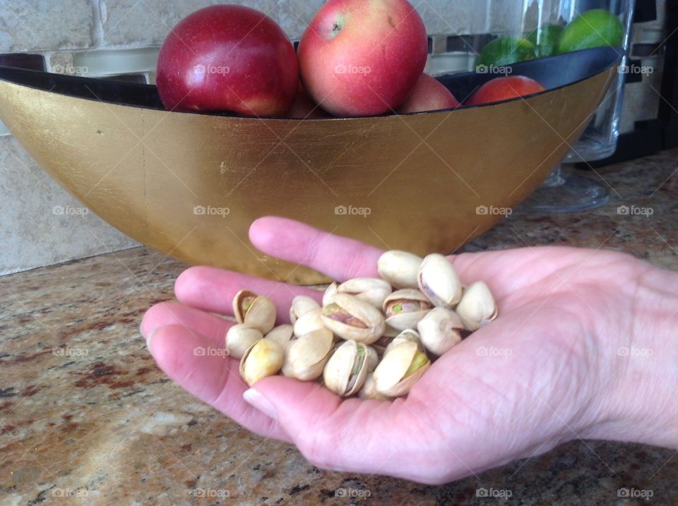 Holding a handful of pistachio nuts.