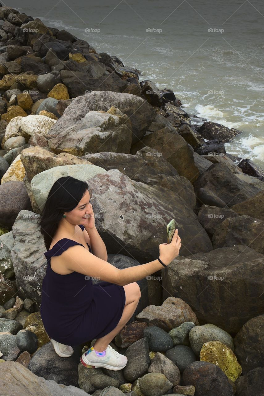 Self portrait using the cell phone. Using the cell phone to take a picture. Woman takes a picture of herself in the sea.