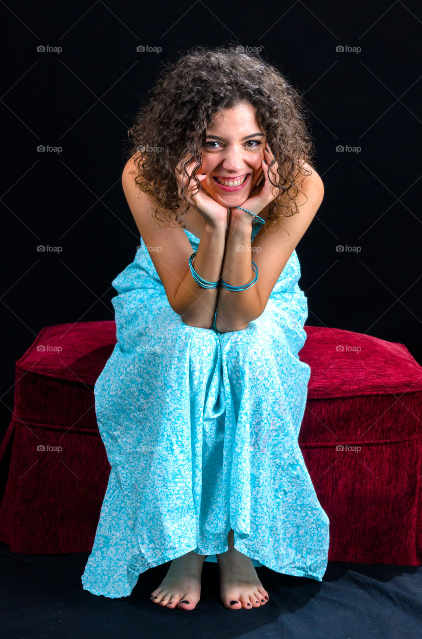 Portrait of a woman with curly hair sitting on sofa and smiling