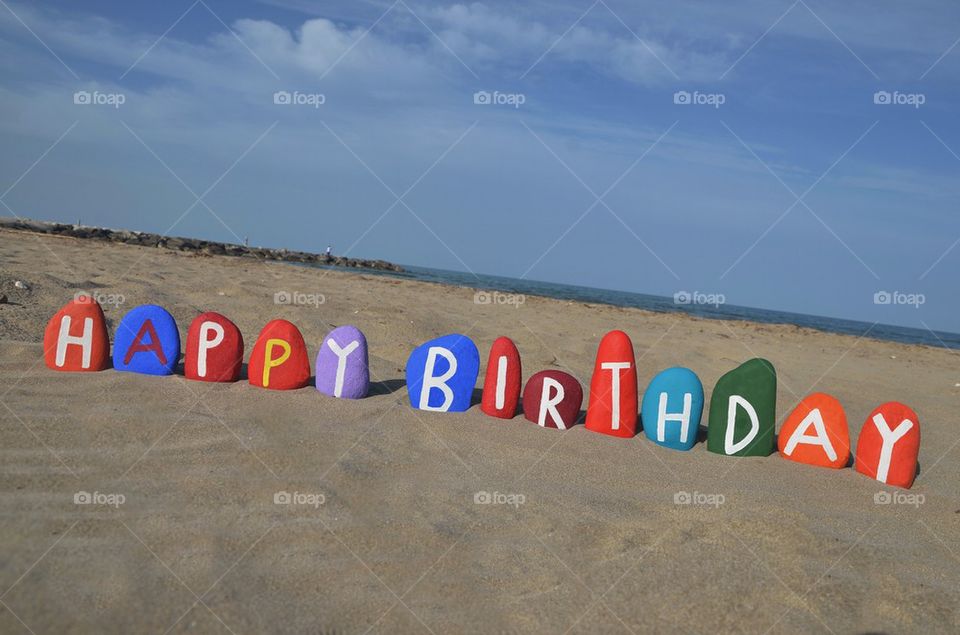 Happy Birthday on colourful stones over the sand