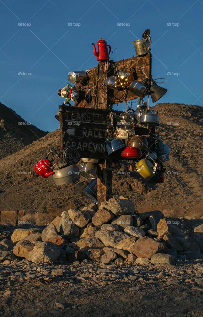 Colored tea pots hanging on a sign post in desert 