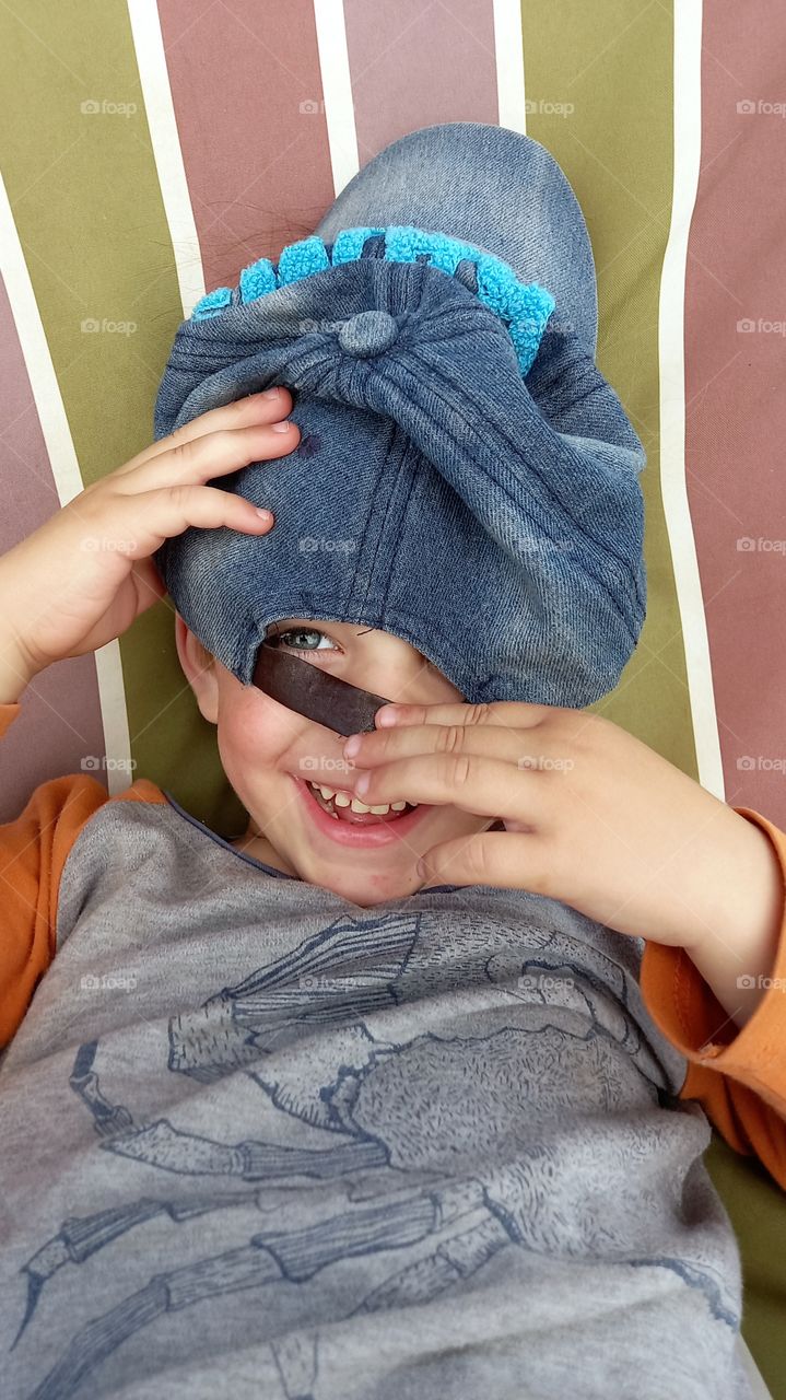 smiling boy with a cap on his face